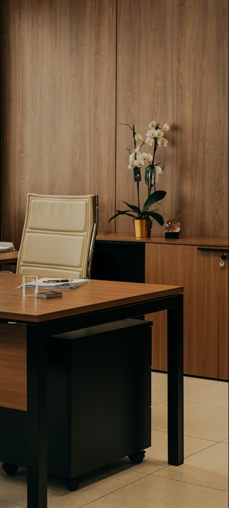 a desk with a chair and a vase of flowers