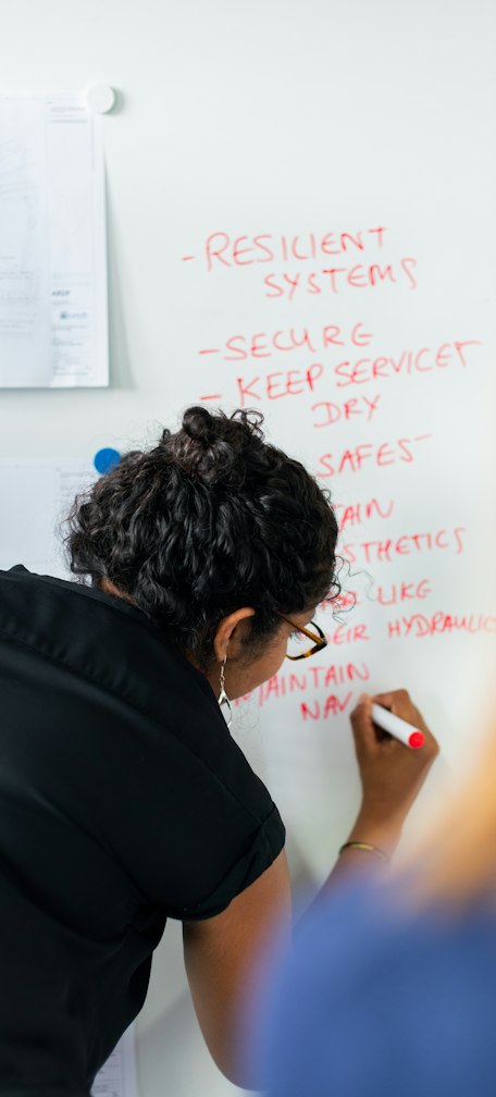 man in black shirt writing on white board
