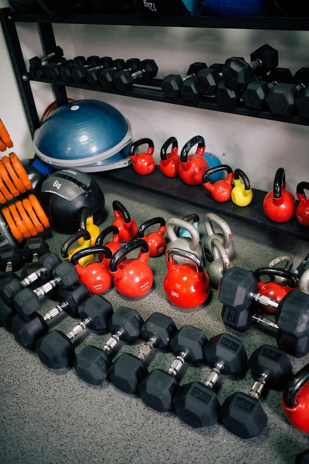 Colourful kettlebells and dumbbells on studio shelves